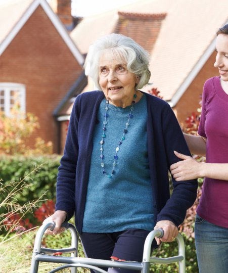 lady caring for elderly lady with a walking frame