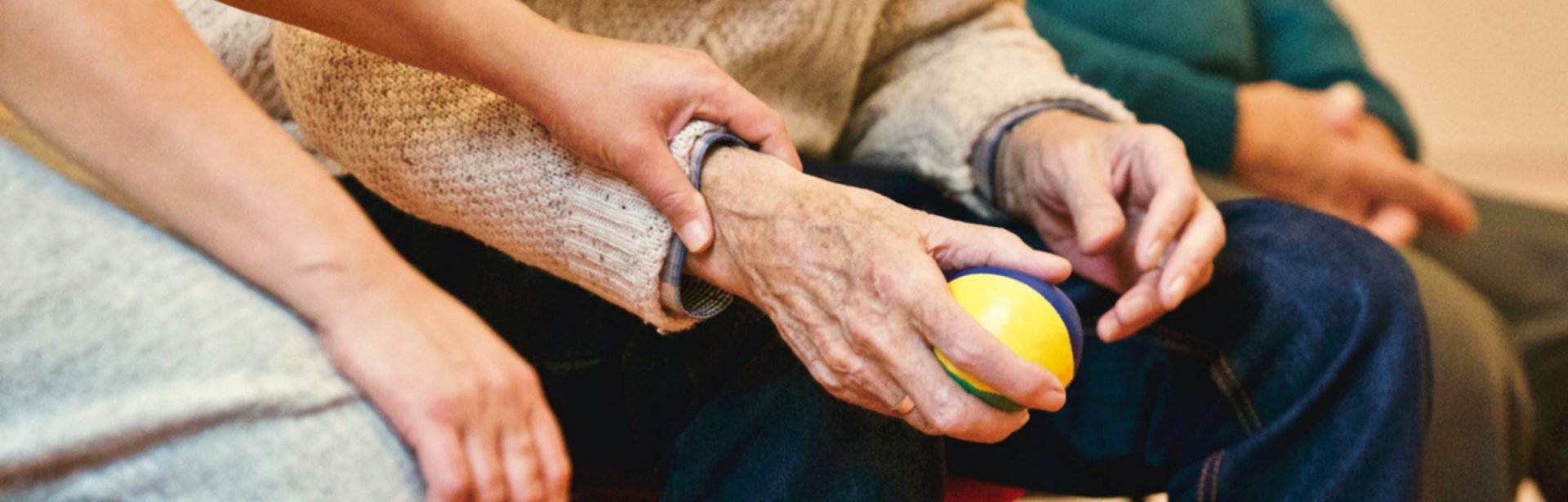 person holding elderly persons hand with a ball in it.